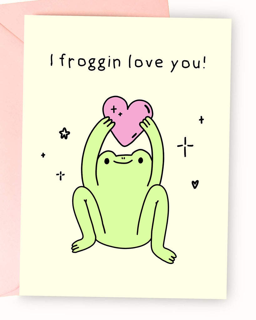 A pastel yellow greeting card featuring an illustration by Nimbob of a happy green frog sitting with its legs spread and arms raised, holding a pink heart. The frog has a cute, content expression, surrounded by sparkles, tiny hearts, and star doodles. The text above reads ‘I froggin’ love you!’ in a playful, handwritten font. A fun and wholesome card, perfect for friendships, anniversaries, or Valentine’s Day.
