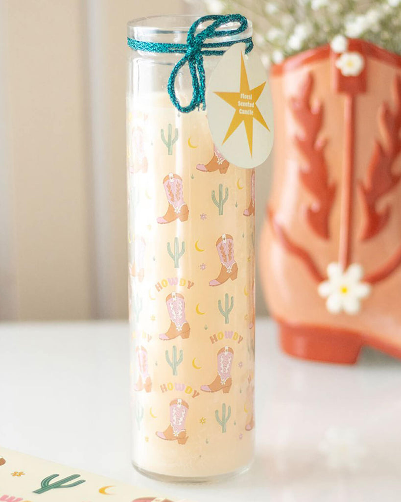 Full view of the Howdy floral candle in a glass tube tied with rustic green twine and featuring pastel Western-themed illustrations.