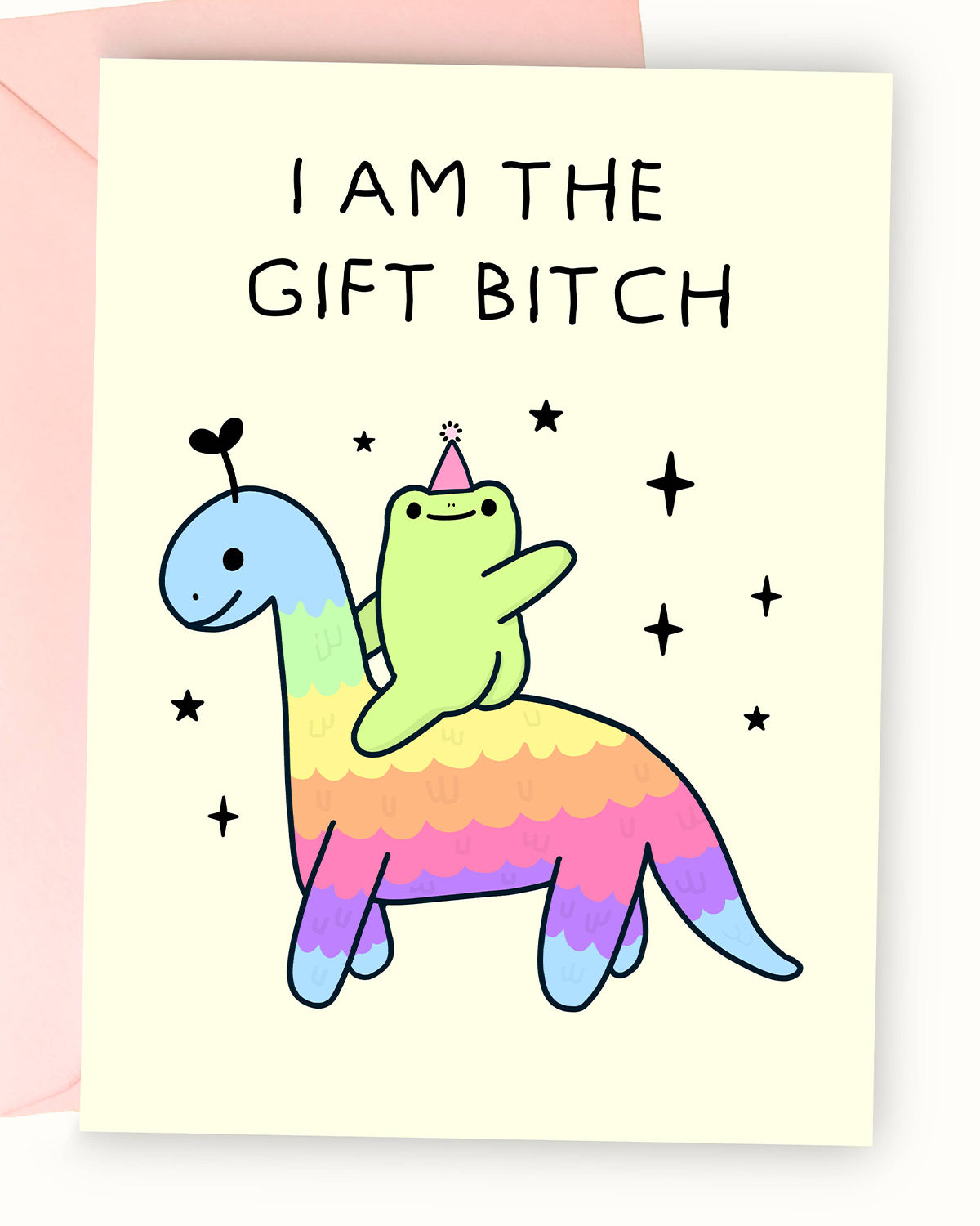 A pastel yellow greeting card featuring an illustration by Nimbob of a cute green frog sitting on a rainbow-coloured dinosaur. The frog wears a tiny pink party hat and raises one arm triumphantly. Above, the bold black text reads ‘I AM THE GIFT BITCH.’ The dinosaur has a friendly face with a tiny heart-shaped antenna, and the background includes scattered sparkles and stars. A fun and sassy birthday card perfect for celebrating in style!