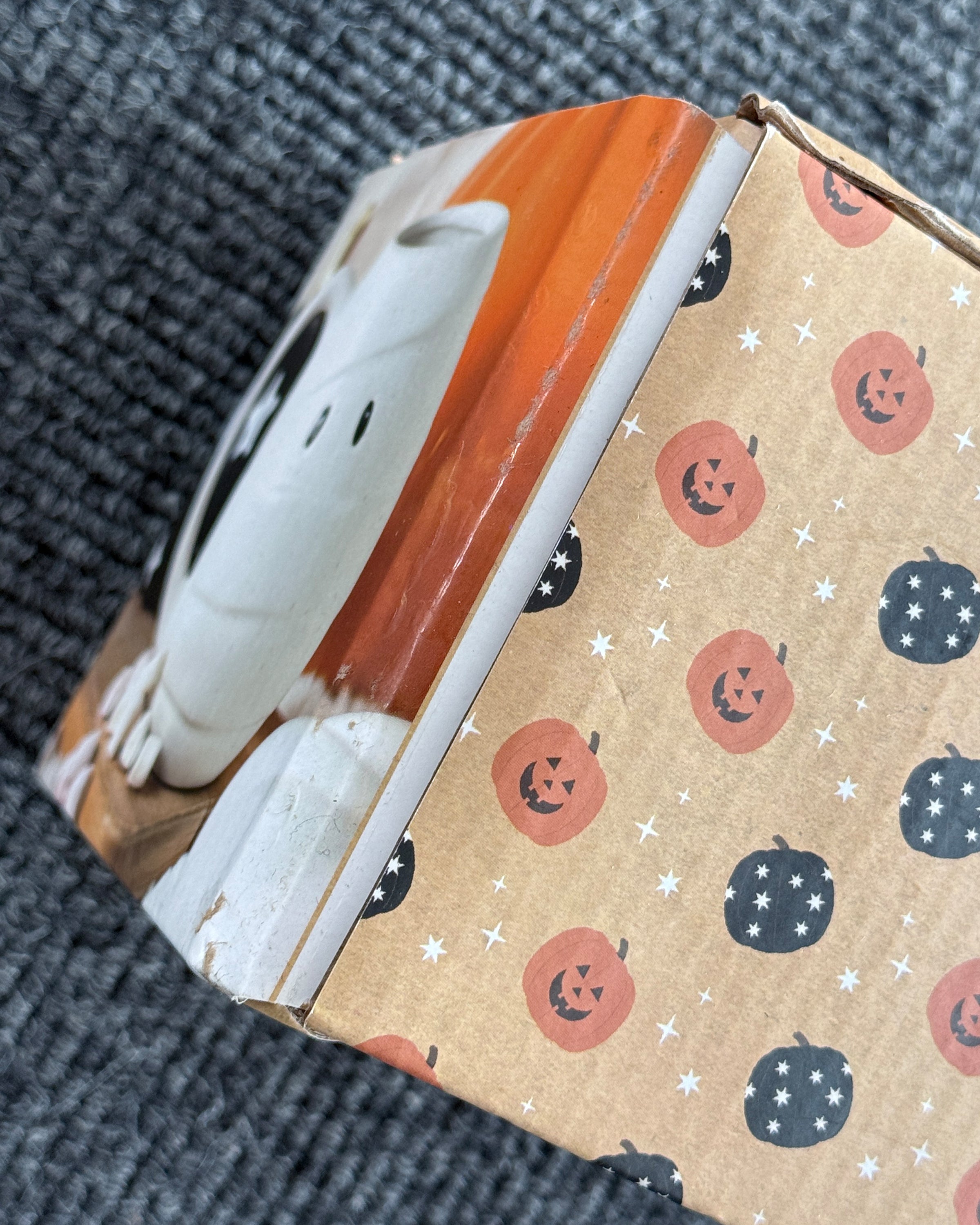 Close-up of Rebel Romance Mummy Shaped Rounded Mug packaging showing slight damage. The Halloween-themed box features black and orange pumpkin designs with stars, highlighting this quirky gothic homeware piece. Perfect for spooky season lovers, millennials, and fans of alternative style. Packaging is damaged but product is unaffected.