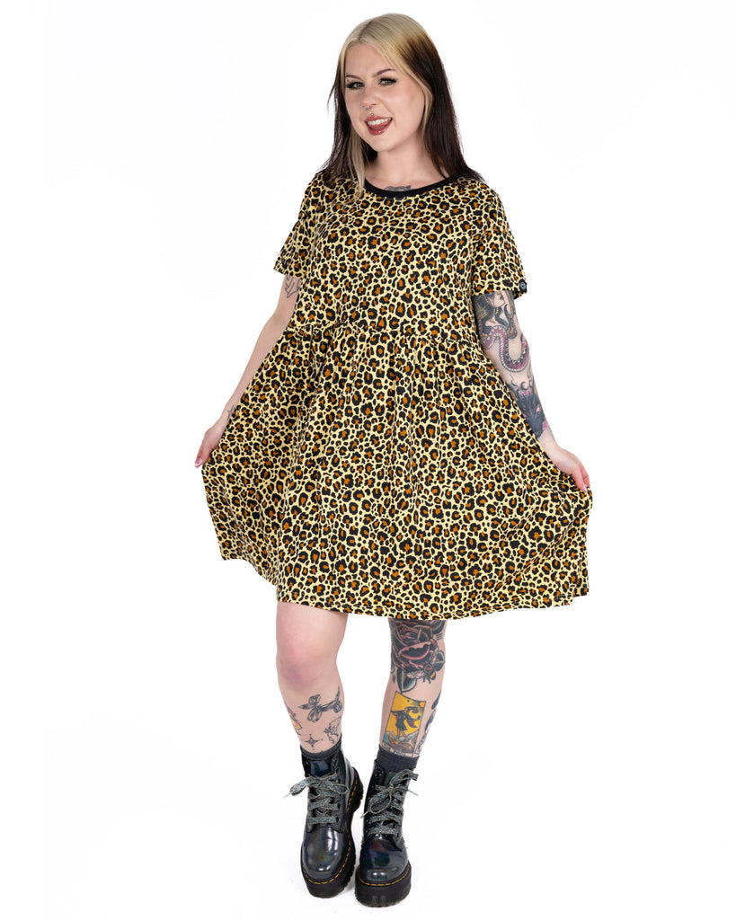 Front-facing image of Florence smiling in the Rebel Romance leopard print dress, holding the skirt to show its floaty shape and relaxed style.