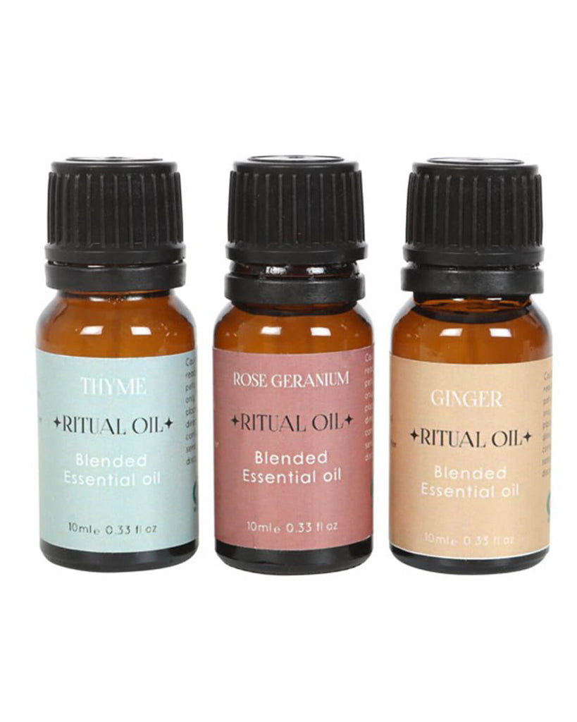 Close-up of three amber glass bottles labeled Thyme, Rose Geranium, and Ginger with black caps.