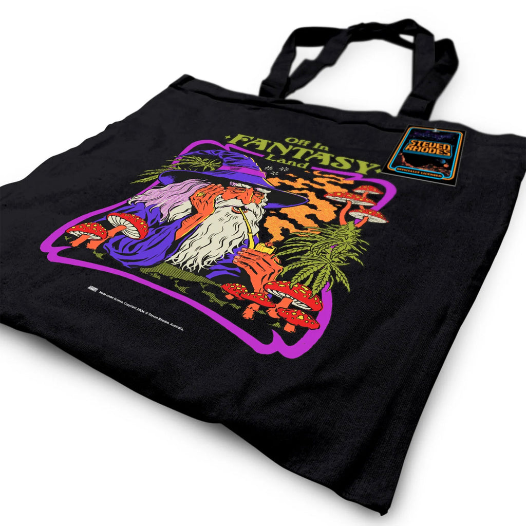Steven Rhodes black tote bag featuring a whimsical design titled ‘Off in Fantasy Land.’ The artwork depicts a wizard sipping a drink surrounded by mushrooms and magical plants, with bold purple, orange, and green tones. The bag includes sturdy handles and an eco-friendly label, combining functionality with quirky charm.