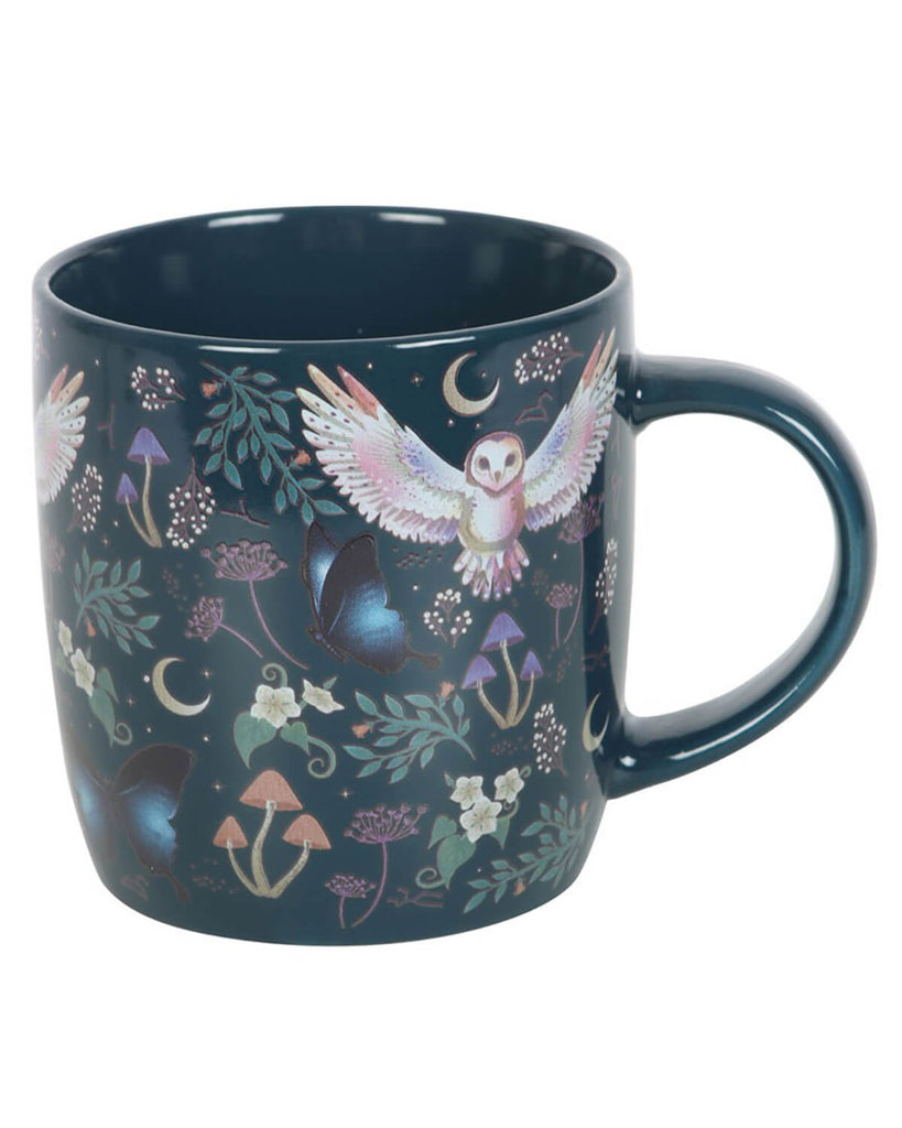  A navy-blue ceramic mug with a detailed all-over print featuring a barn owl in flight, crescent moons, butterflies, mushrooms, and forest foliage. The mug has a glossy finish and a sturdy handle.
