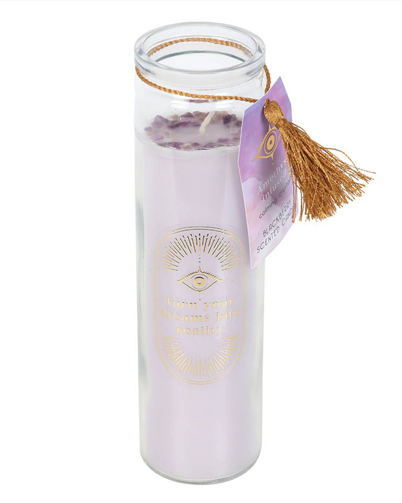 The candle burning, placed on a table with a golden tassel and purple tag attached, creating a peaceful, relaxing vibe.