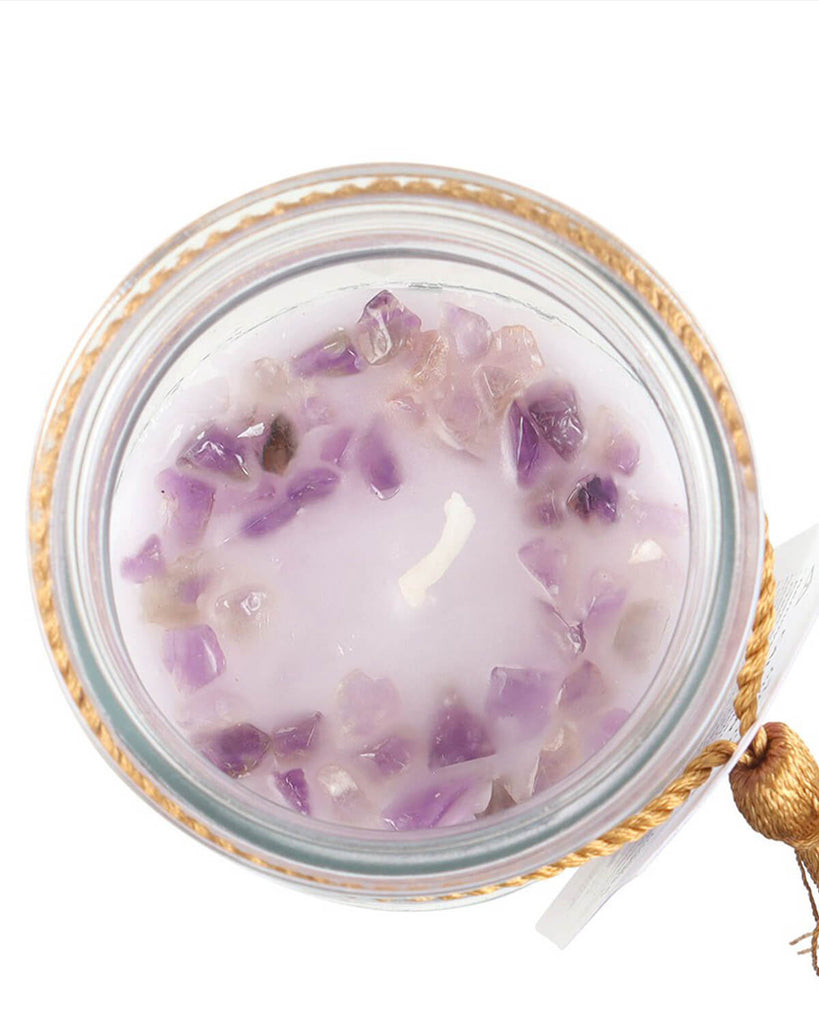 Top-down view of the candle, showing purple amethyst chips scattered around the white wax.