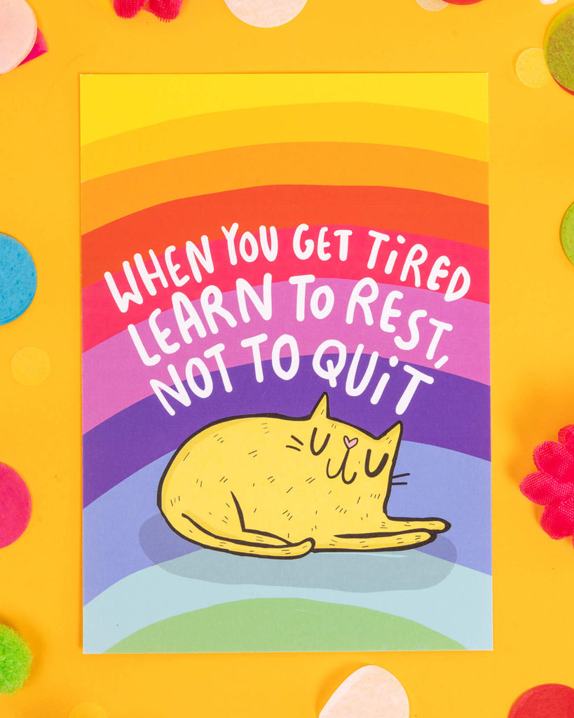 A bright A6 postcard featuring a sleeping yellow cartoon cat under the phrase “When You Get Tired Learn to Rest, Not to Quit” on a rainbow background. Designed by Katie Abey, this calming and motivational postcard is perfect for millennials into alternative stationery, mental health positivity, and colourful self-care reminders.