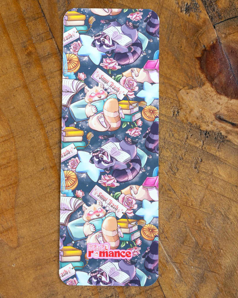 A single Smut Trash bookmark featuring a dreamy night scene with raccoons and red pandas reading, surrounded by flowers, books, and stars. Rebel Romance logo at the bottom.