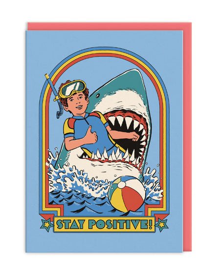 “Stay Positive!” Shark Card: A whimsical card depicting a child giving a thumbs-up while being eaten by a shark, combining dark humour with vibrant seaside imagery.