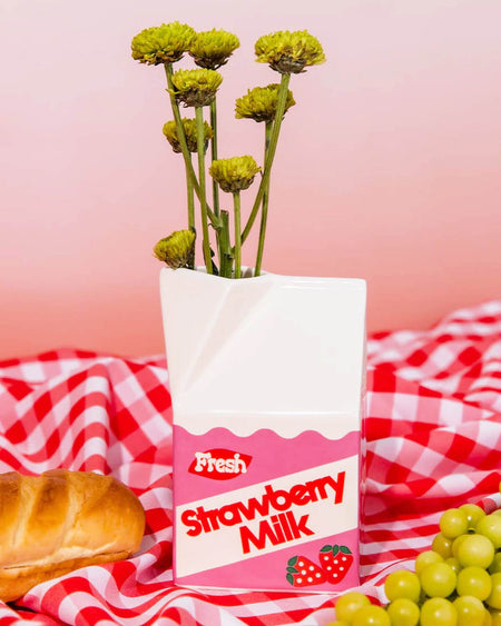 Close-up of a ceramic strawberry milk vase with a retro design, featuring a pink and white milk carton shape with “Fresh Strawberry Milk” text and cute strawberry illustrations. Perfect for flowers, stationery, or decor.
