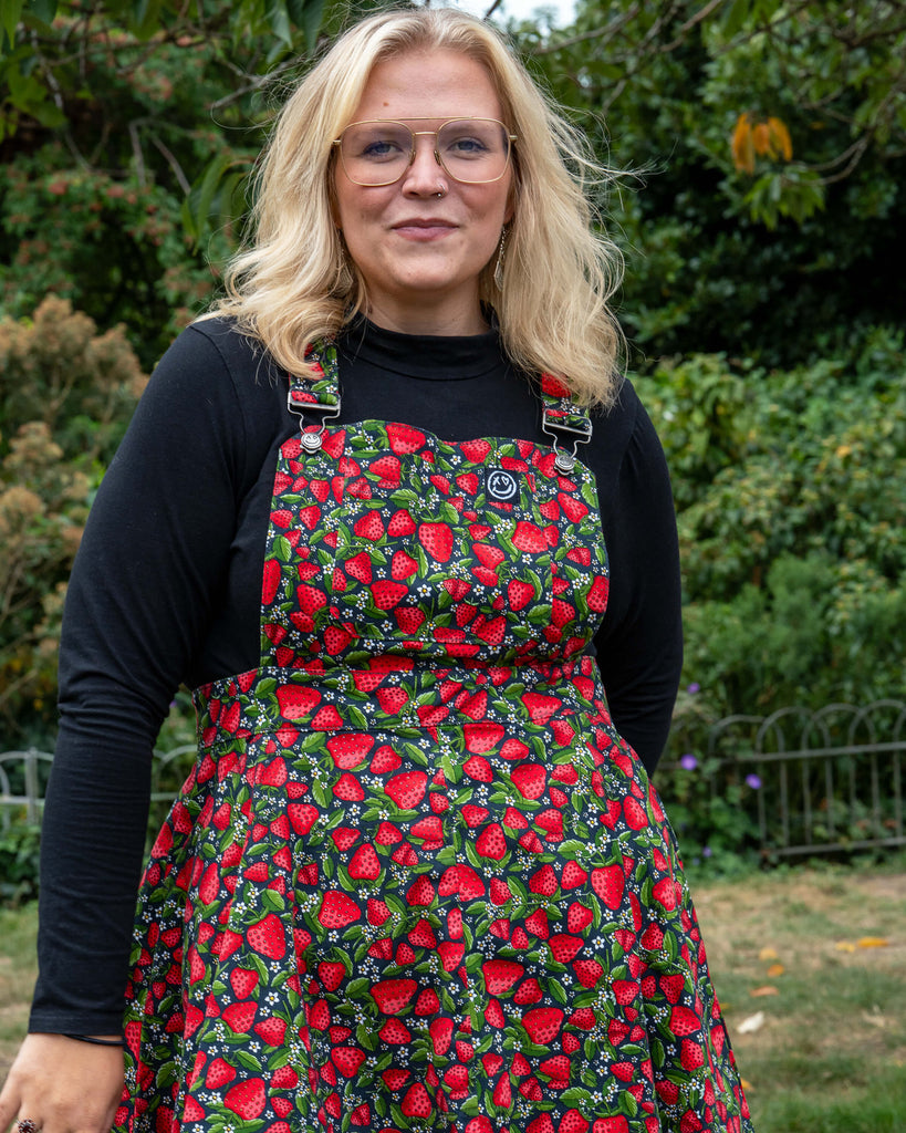 Outdoor photo of Betty  in the Rebel Romance Strawberry Field Flared Pinafore, a playful summer dress made ethically in India.