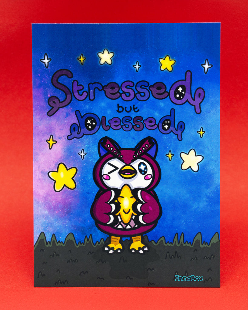 A colourful Innabox Stressed But Blessed Celeste Postcard featuring a cute owl character holding a glowing star fragment. The background shows a dreamy night sky with bright yellow stars and soft purple and blue tones. This disability inspired uplifting postcard is printed on 350gsm silk board and is blank on the reverse. Ideal for gifting, collecting, or displaying as positive art.