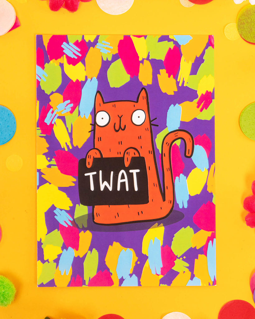 A colourful A6 postcard featuring a cartoon orange cat holding a sign that says “TWAT” against a neon paint splatter background. Designed by Katie Abey, this bold and sweary card is perfect for alternative humour fans, millennials who love quirky stationery, and gifting to mates with a naughty sense of fun.