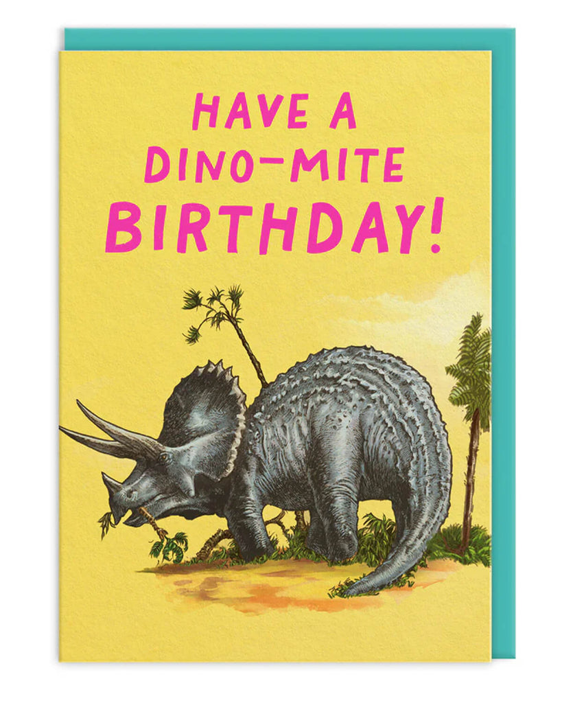 Triceratops birthday card with a vintage-style dinosaur illustration on a bright yellow background and bold pink text that says “Have a Dino-Mite Birthday!” paired with a turquoise envelope.