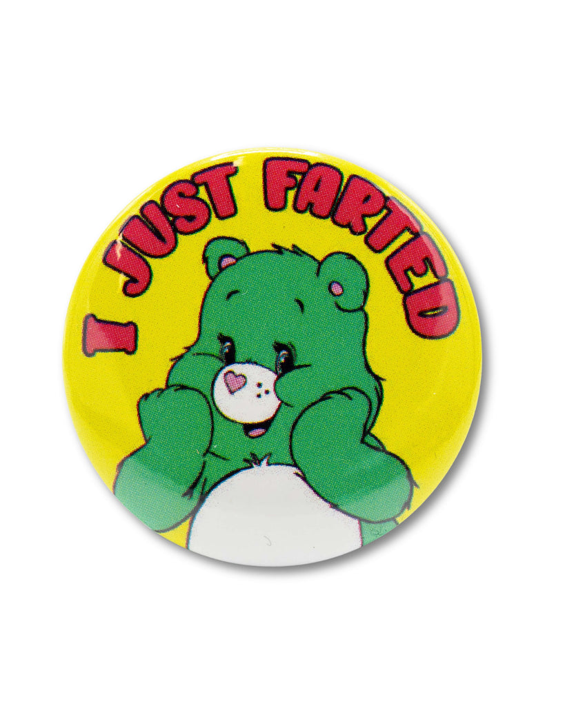 Yellow button badge with a smiling green care bear character and red bubble text that reads 'I Just Farted' above. An 80s cartoon style design from Bite Your Granny.
