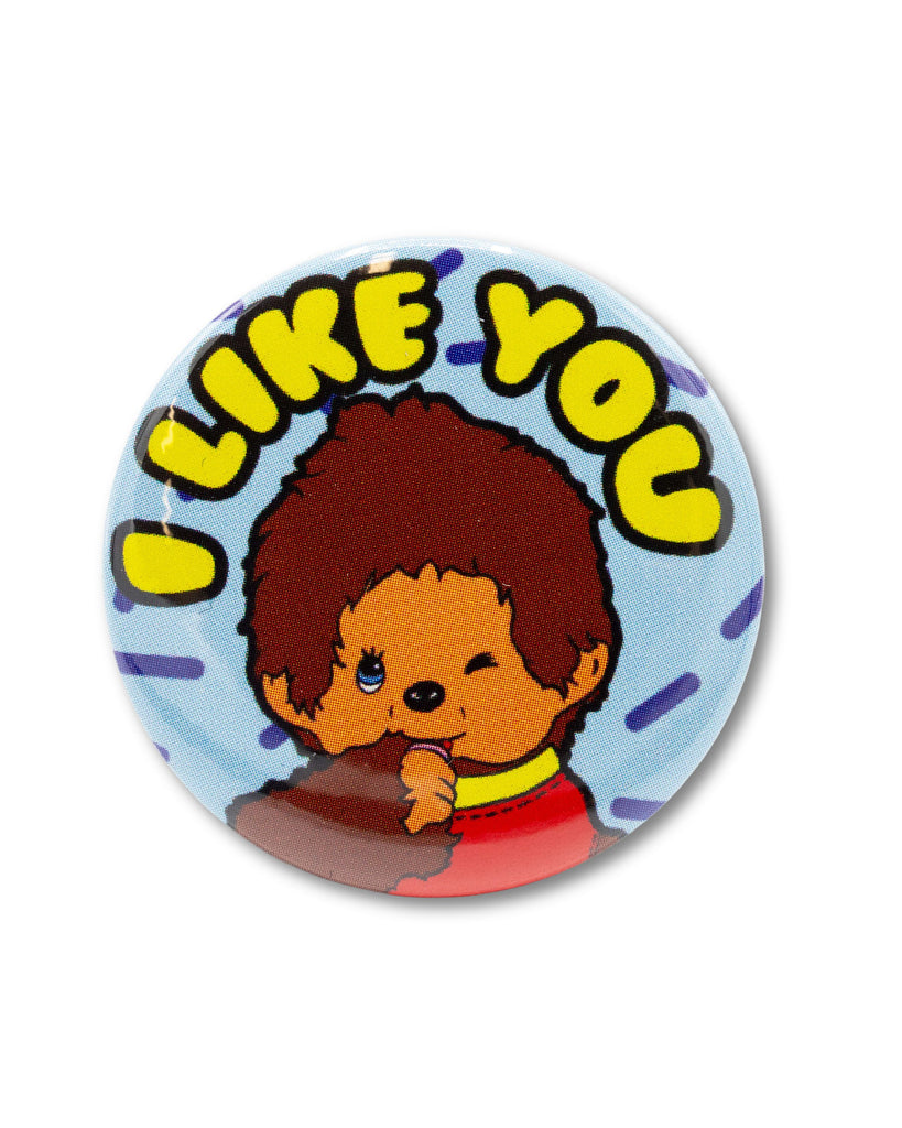 Blue button badge with monchhichi the monkey winking with yellow bubble writing reading 'I LIKE YOU' above. Retro design pin badge from Bite Your Granny.
