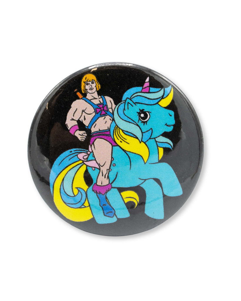Black button badge with a cartoon character, he man, riding a blue my little pony unicorn. A retro 80s design from Bite Your Granny.