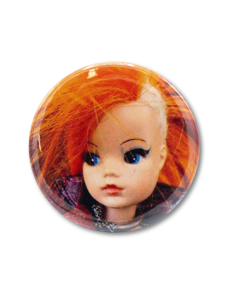 Button badge with a doll's face featuring red hair and blue eyes, a retro punk sindy design from Bite Your Granny.