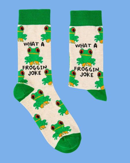 Beige socks with cartoon frog illustrations and “What a Froggin’ Joke” slogan by Urban Eccentric, styled flat on a blue background. Sold at Rebel Romance.
