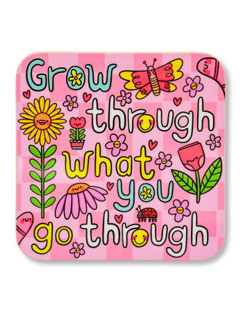 Bright pink square drinks coaster featuring the motivational phrase “Grow through what you go through” in playful, colourful text. The design includes cheerful cartoon flowers, a butterfly, ladybird, hearts, and smiling faces. Illustrated by Kellylou for Rebel Romance, a small UK business that celebrates alternative style and joyful self-expression. Glossy hardboard MDF finish makes it a bold and fun gift or homeware piece.