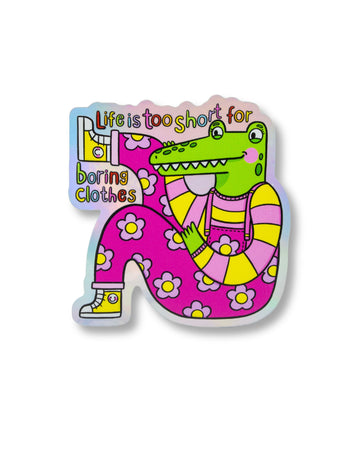 Holographic vinyl sticker from Rebel Romance featuring a bright green crocodile in dopamine-dressing floral overalls with the slogan “Life is too short for boring clothes.” Designed by Kellylou, this waterproof matte sticker celebrates quirky, bold fashion and alternative style. Perfect for customising laptops, notebooks, or mirrors. Ideal for fashion lovers and sticker collectors.