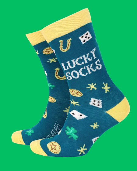 Close-up of Smiling Faces bamboo Lucky Socks, teal-coloured with bright lucky symbols like dice, clovers, and horseshoes, featuring contrasting yellow trims. Sustainable and stylish novelty socks from Rebel Romance