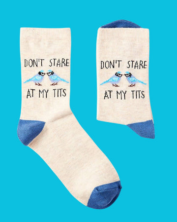Pair of Urban Eccentric socks with beige background, blue detailing, and humorous bird pun slogan “Don’t Stare at My Tits.” Stocked by Rebel Romance.