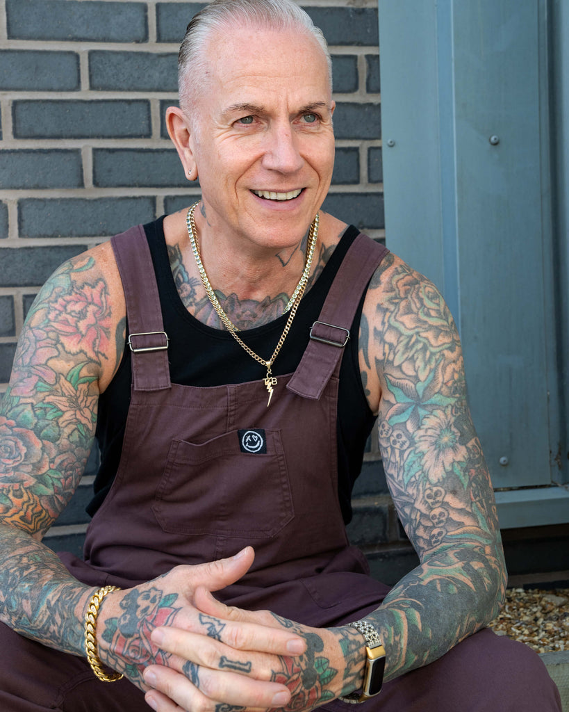 Close-up portrait of James smiling in the Plum Mocha dungarees with the bib and pocket detail visible.