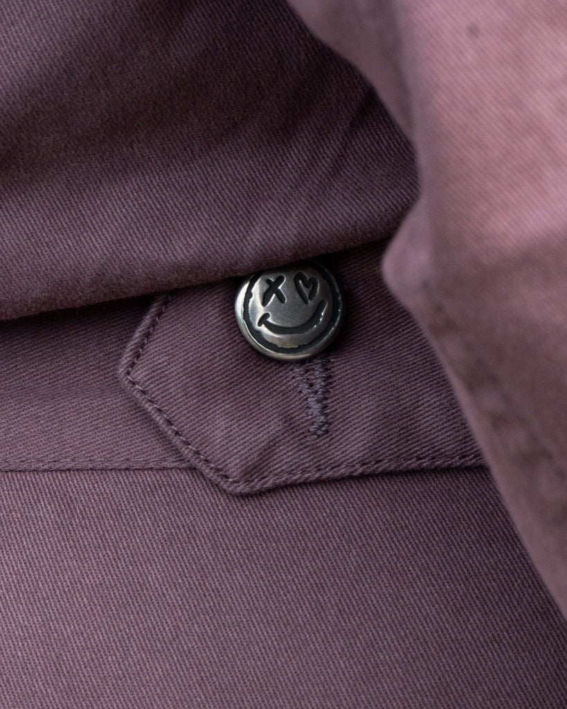 Close-up of a button on a PLUM MOCHA garment with a brand logo.