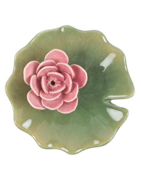 Close-up of a pink water lily incense holder on a green lily pad-shaped ceramic dish. The small hole in the centre of the flower securely holds an incense stick while the dish catches the falling ash.