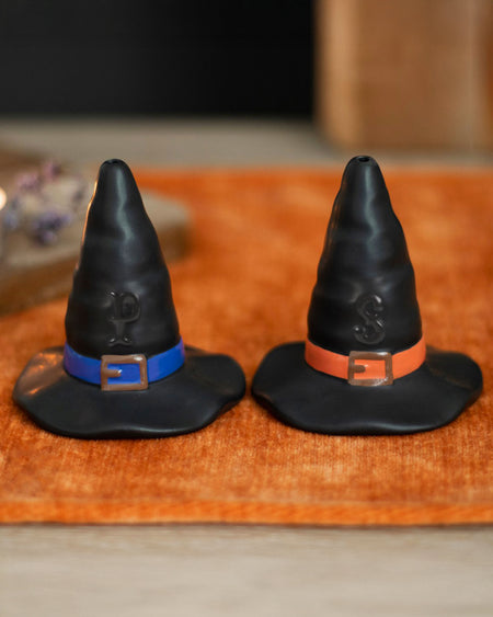 A pair of black ceramic salt and pepper shakers shaped like classic witch hats. Made from dolomite and designed for Halloween or gothic kitchen decor. Each shaker is food safe and measures approximately 7.5cm high by 7cm wide. A fun, spooky addition to seasonal dining or witch-themed interiors.