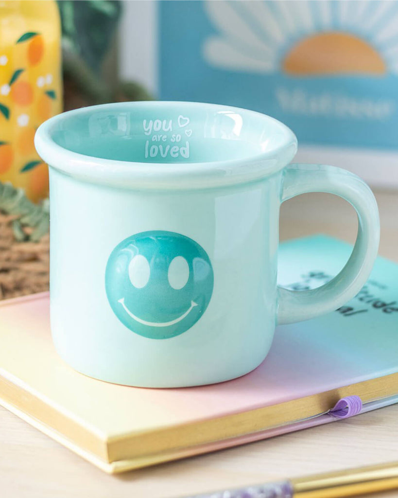 Styled image of the mug on a pastel notebook with a pen, creating a cosy, positive vibe.