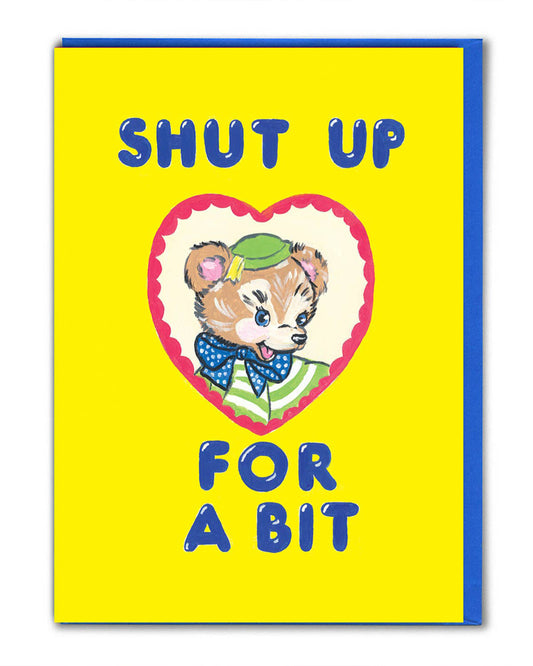 Rebel Romance funny greeting card illustrated by Magda Archer featuring the phrase "Shut Up For A Bit" in bold blue text on a bright yellow background. A retro-style bear character with a green hat and polka dot bow tie sits inside a heart-shaped frame. Perfect quirky card for millennials who love bold, kitschy artwork with a darkly humorous twist.