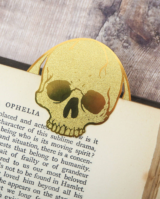 Gold brass skull bookmark by Literary Emporium clipped over a vintage Hamlet book page. Sold by Rebel Romance, a UK brand celebrating alternative style, gothic homeware and unique gifts for millennials.