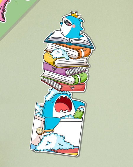 Toastedink shark bookmark from Rebel Romance, showing a crowned shark in a bubbly bath holding a book, with a tower of smiling books stacked on its nose. Shown against a soft green backdrop.
