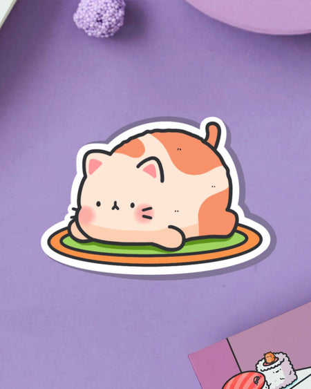 Cute Resting Cat Vinyl Sticker by Toastedink, stocked by Rebel Romance. Features an illustrated chubby orange and white cat with puffy cheeks lying on a green rug with an orange border, shown on a lilac-purple surface. Perfect kawaii sticker for laptops, water bottles, and notebooks. Ideal for cat lovers and fans of quirky, alternative aesthetics.