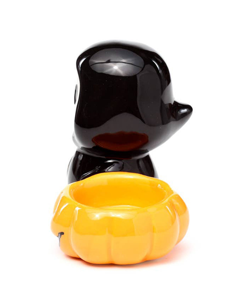 Side angle of the Ceramic Skull Boy Tea Light Holder by Rebel Romance. The cute skull-faced figure in a black cloak stands beside a carved orange jack-o'-lantern bowl—ideal for Halloween table décor or gifting.