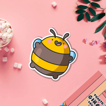 Glossy vinyl sticker of a round, cartoon-style yellow and brown bumblebee jumping happily with pink cheeks and arms raised. Displayed on a blue background. Fun and cute waterproof sticker, perfect for decorating laptops and notebooks.