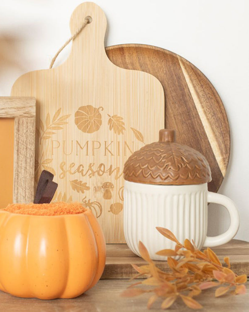 Styled autumnal setup featuring Rebel Romance's Autumn Acorn Shaped Mug with a ribbed cream base and acorn lid, placed next to a pumpkin pot and rustic wooden décor. Cosy seasonal vibes perfect for millennial homeware lovers.
