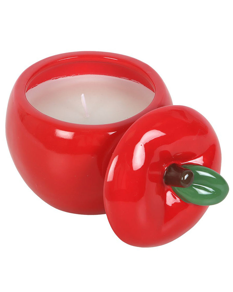 Overhead view of an apple-shaped ceramic candle jar with the lid off, displaying the unlit white wax candle inside. The lid has a green leaf and brown stem detail.