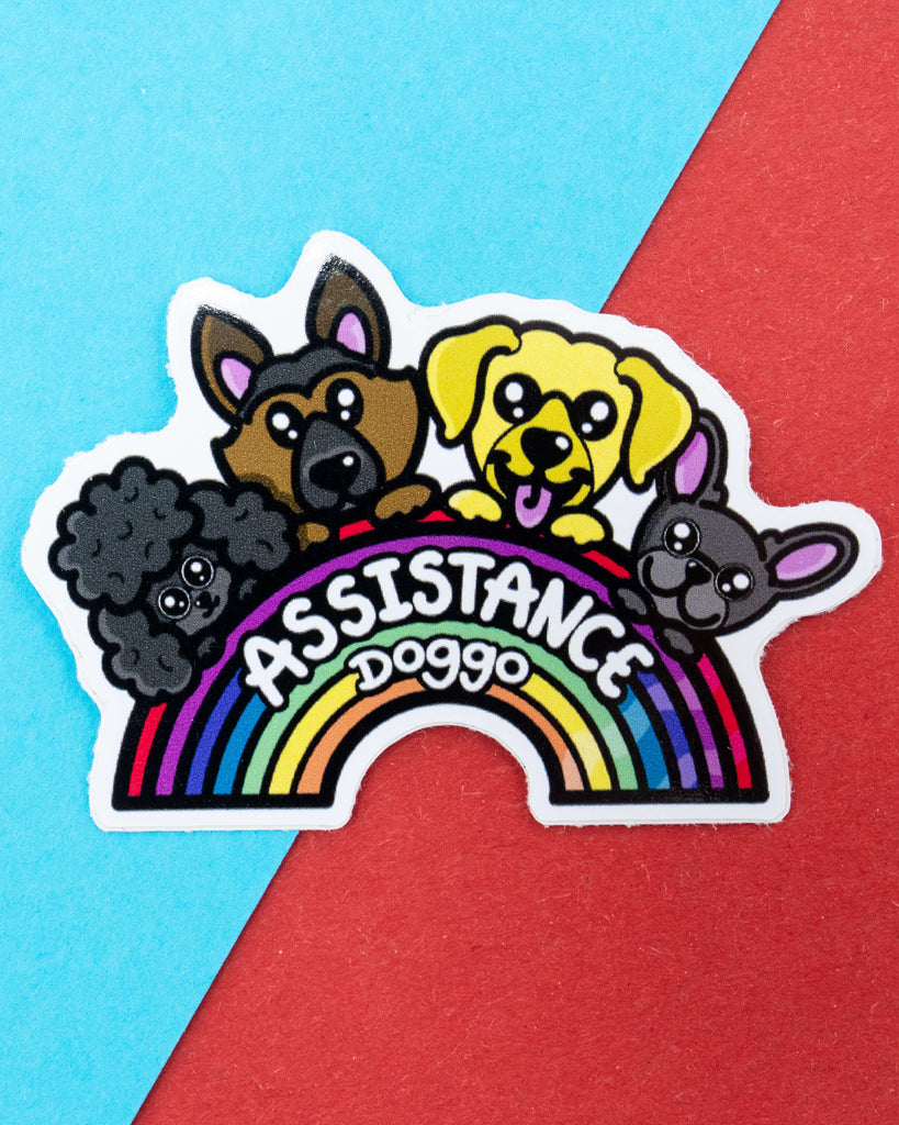 Cute rainbow-shaped vinyl sticker featuring four cartoon dogs of different breeds above the text "Assistance Doggo", designed by Innabox and sold by Rebel Romance. Celebrates and raises awareness for assistance dogs who support disabled and chronically ill people. A waterproof sticker perfect for mobility aids, notebooks, and emotional support snack boxes.