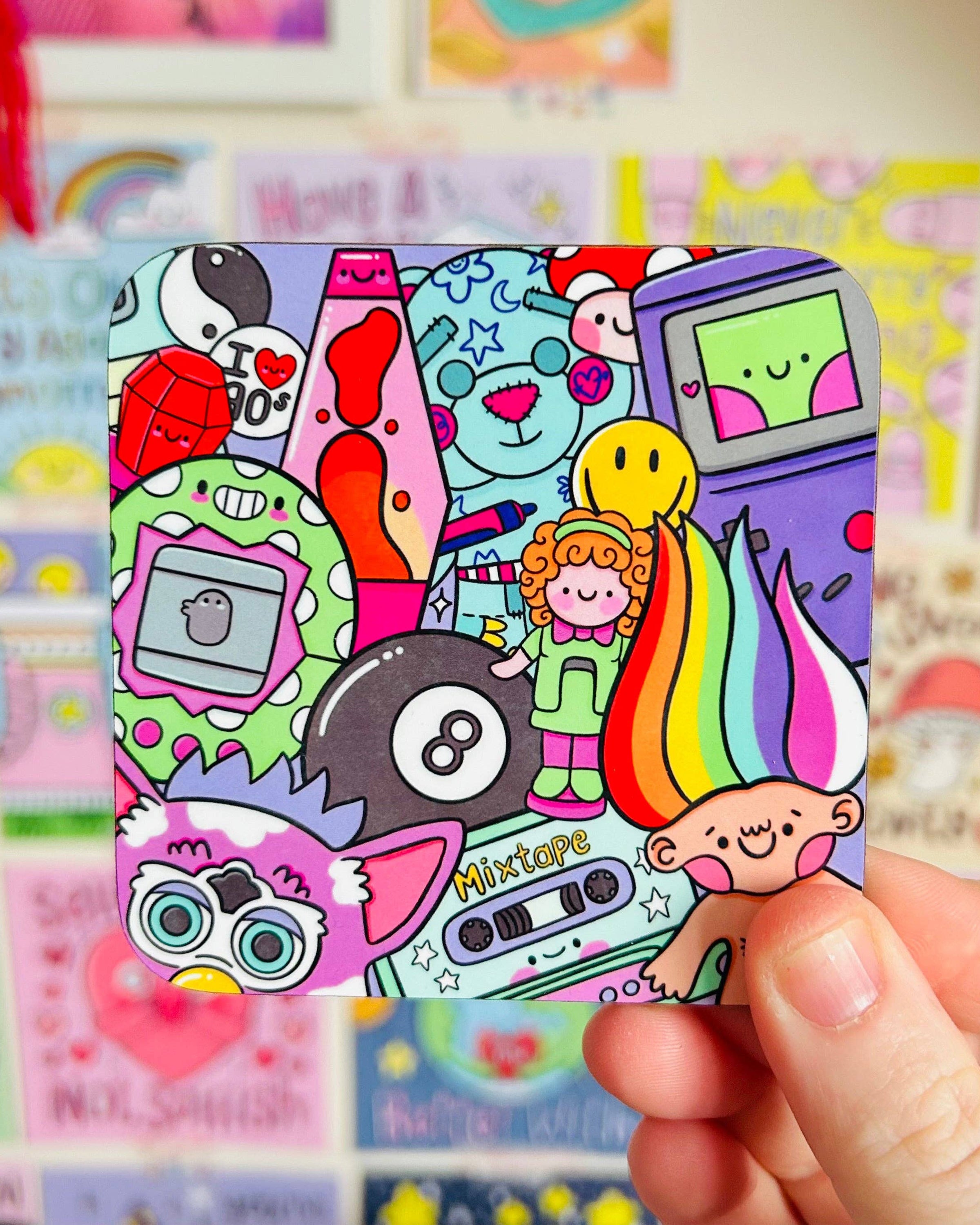 A hand holds up the Rebel Romance 90’s Nostalgia coaster designed by Kellylou. The square coaster features a playful and vibrant collage of 90s-themed icons like a rainbow troll, mixtape, Furby, and lava lamp. Bright pastel colours and a glossy finish make it a bold retro gift for millennials.