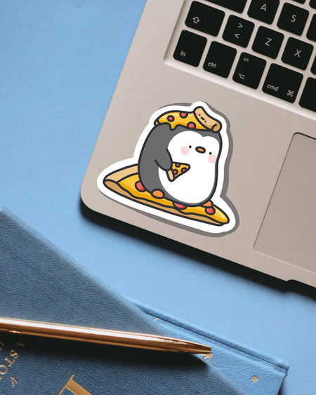 Cute Pizza Penguin Vinyl Sticker by Toastedink on a laptop. Features an adorable cartoon penguin sitting on a slice of pepperoni pizza while holding another and wearing one as a hat. Stocked by Rebel Romance and printed on glossy waterproof vinyl.
