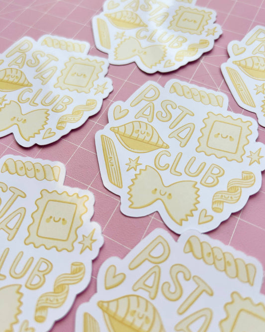 Glossy vinyl stickers from Rebel Romance displayed on a pink cutting mat, featuring the phrase "Pasta Club" with cute illustrated pasta shapes like farfalle, ravioli, fusilli and conchiglie in soft yellow tones. Designed by Kellylou and ideal for food lovers and sticker collectors.