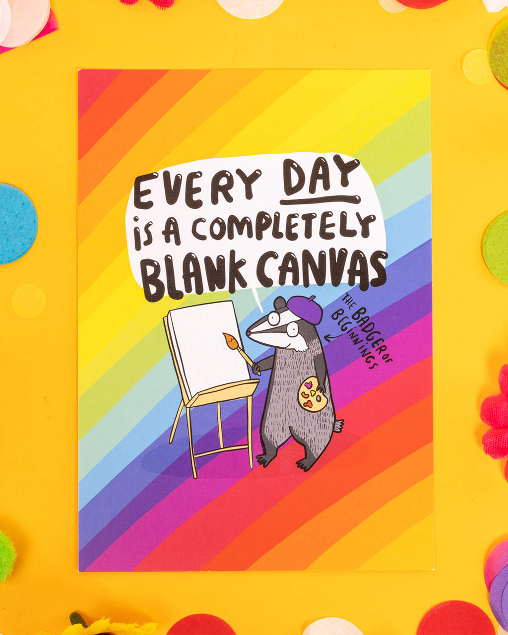 Colourful A6 postcard featuring a rainbow-striped background and an illustrated badger in a beret painting on a blank canvas. Text reads “Every day is a completely blank canvas” in bold lettering. A fun and inspiring design by Katie Abey, ideal for millennials into witchy, creative, alternative aesthetics and dopamine decor.