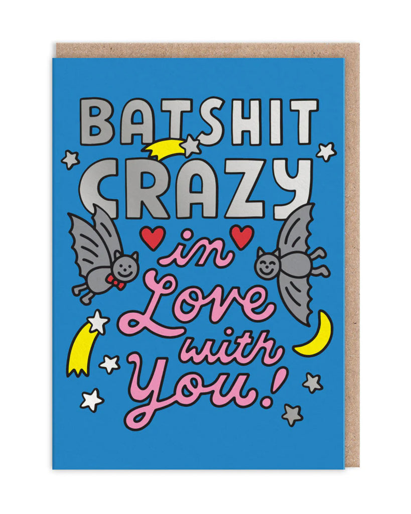 The “Batshit Crazy in Love With You” greeting card propped up, showcasing its humorous design against a black background. The blue card is paired with a kraft envelope.