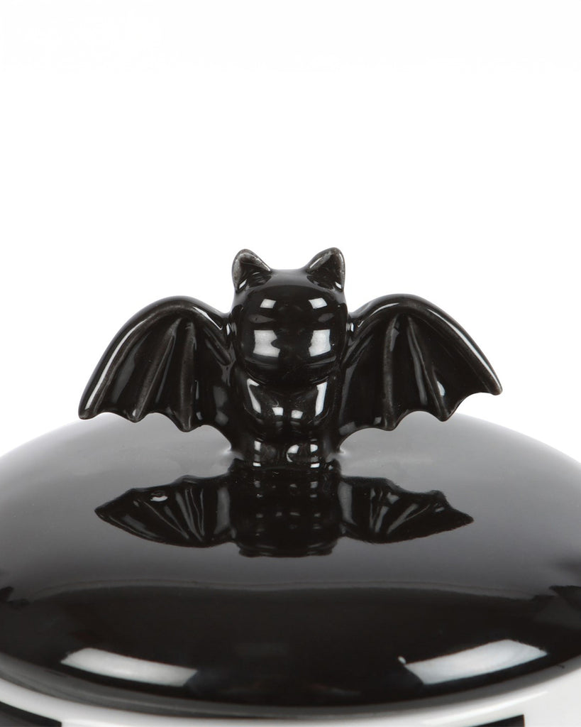 A close-up of the bat detail on the storage jar lid, showcasing the glossy black ceramic with its adorable, outstretched wings. A statement piece for goth and Halloween lovers.