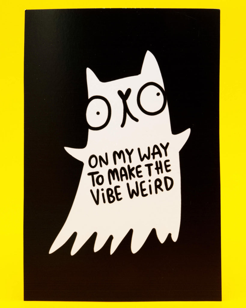 Black A6 postcard featuring a white ghost cat illustration by Katie Abey with wide eyes and a quirky expression. The ghost cat has the text On My Way To Make The Vibe Weird printed on its body. The postcard is displayed against a bright yellow background. Fun spooky design for fans of weird art and positive vibes.