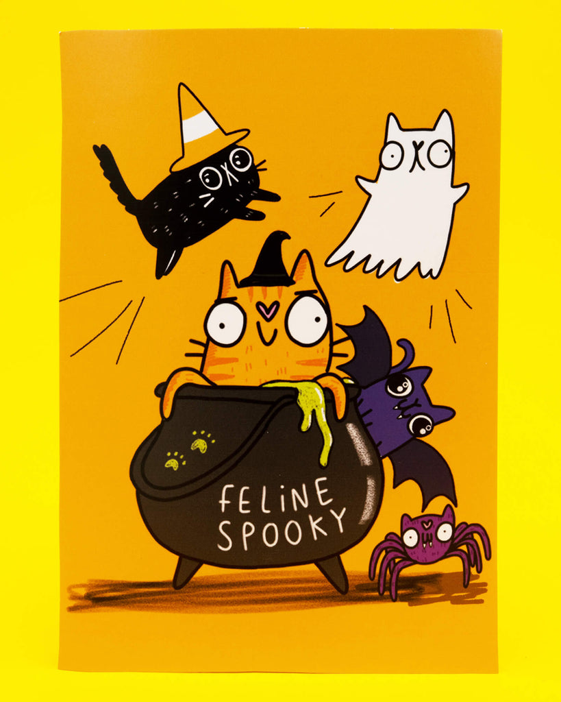 Bright orange A6 postcard featuring Katie Abey’s Feline Spooky Halloween Cats illustration. An orange witch cat sits in a bubbling cauldron marked Feline Spooky, surrounded by a black cat in a candy corn hat, a ghost cat, a bat and a purple spider. Printed on 350gsm silk card and perfect for Halloween gifting or decorating.