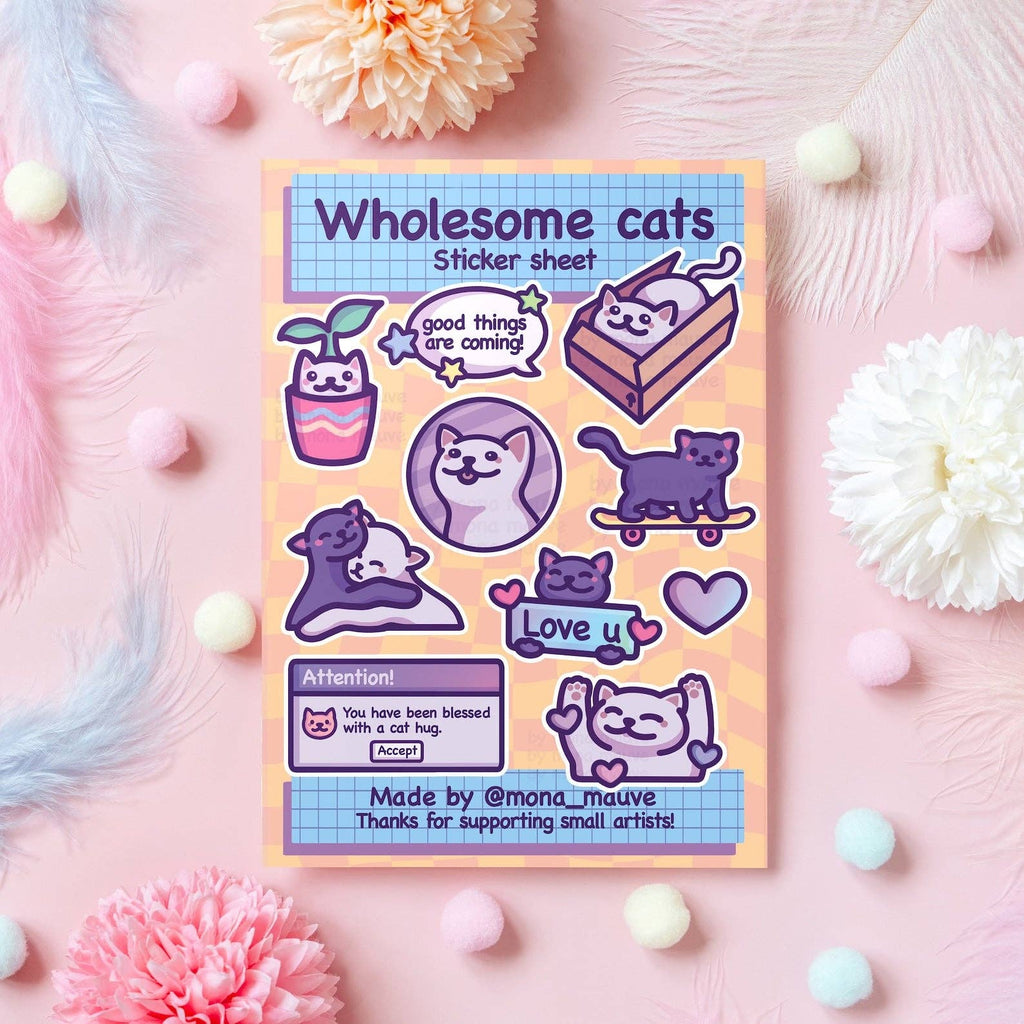 Flat lay of the Wholesome Cats Sticker Sheet by Mona Mauve, featuring 10 waterproof vinyl stickers of cute illustrated cats in positive, uplifting designs. Includes captions like “good things are coming” and “Love u,” plus hugging cats, skateboarding cats, and a computer pop-up saying “You have been blessed with a cat hug.” A cheerful gift for cat lovers and stationery fans.